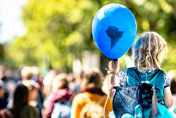 Crowd of people with a child holding a blue balloon.