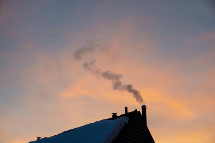 roof with smoking chimney with sunset in the backdrop
